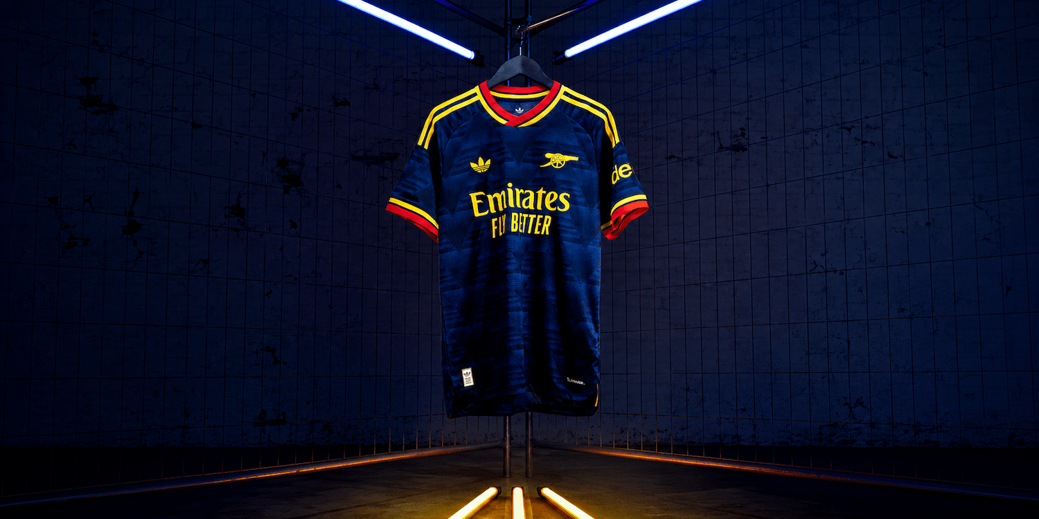 27 Away Jersey in navy and yellow hanging under blue lights